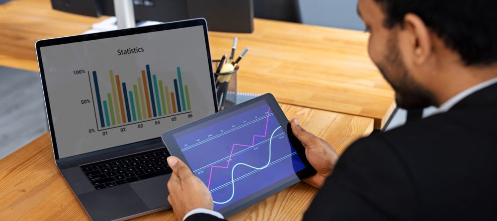 A man Using Tab and system to check Why UK/US Companies Are Investing in BI Development Now More Than Ever